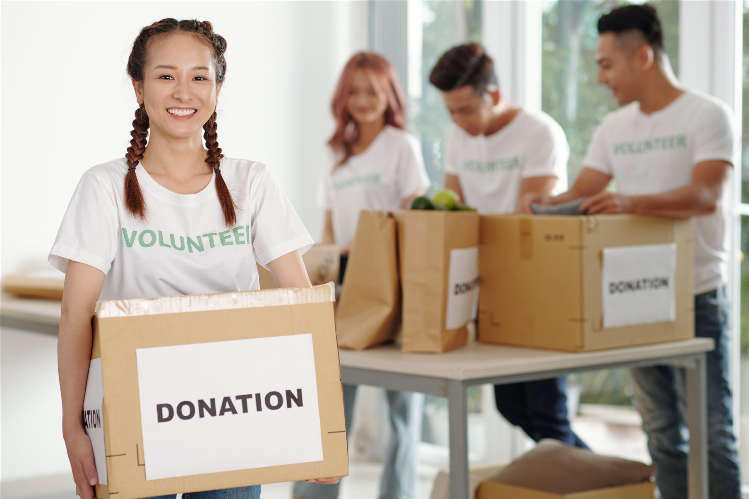 Young volunteers in white shirts packing donation boxes
